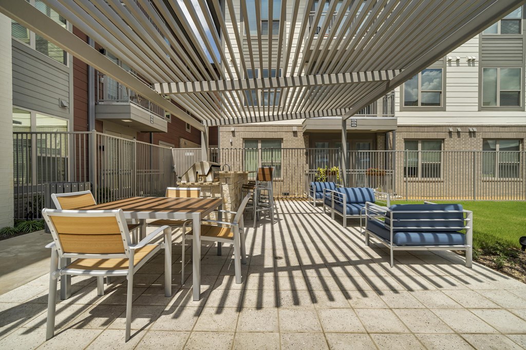 A patio with a table and chairs under a striped awning.