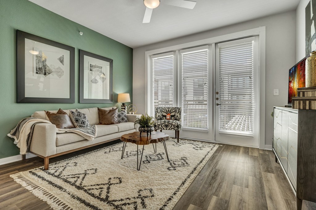 A living room with a couch, a coffee table, and a rug with a pattern on it.