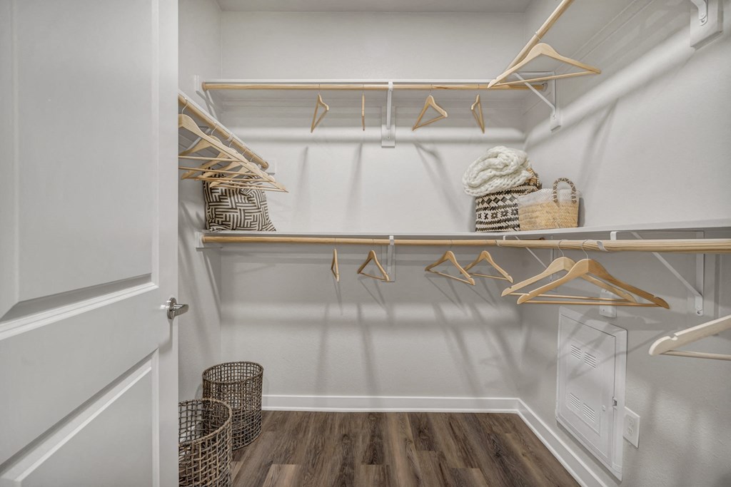 A white closet with wooden hangers and baskets.