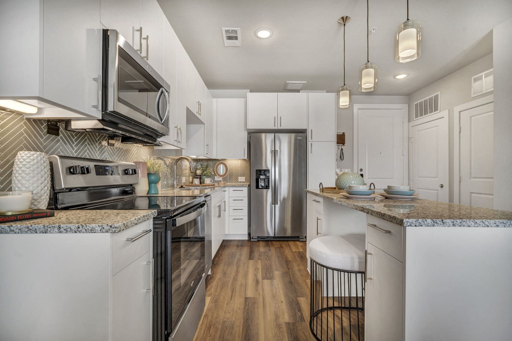 A modern kitchen with white cabinets and stainless steel appliances.