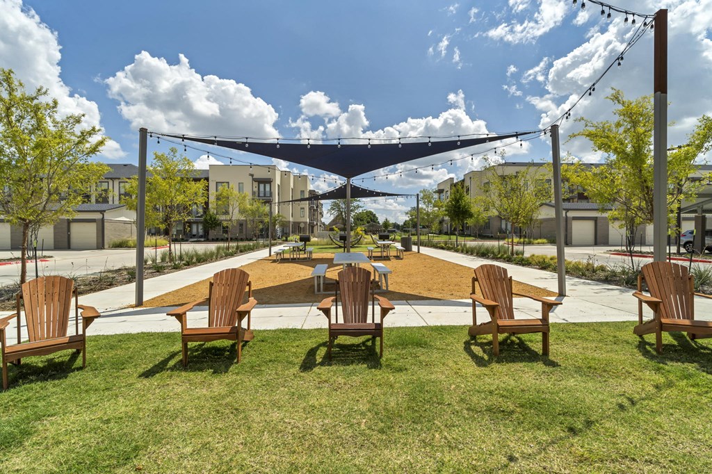 A shaded outdoor seating area with wooden chairs.