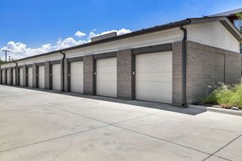 A long building with a grey roof and white garage doors.