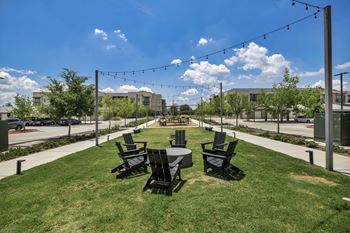 A sunny day at a park with black chairs and tables.