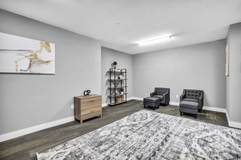 A room with a grey carpet and a grey sofa.