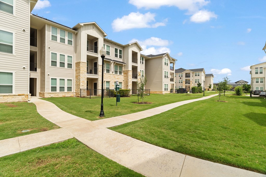 Apartment complex with a grassy area and a crosswalk.