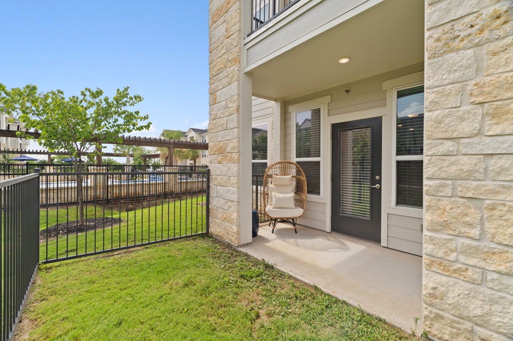 A house with a black gate and a chair on the porch.