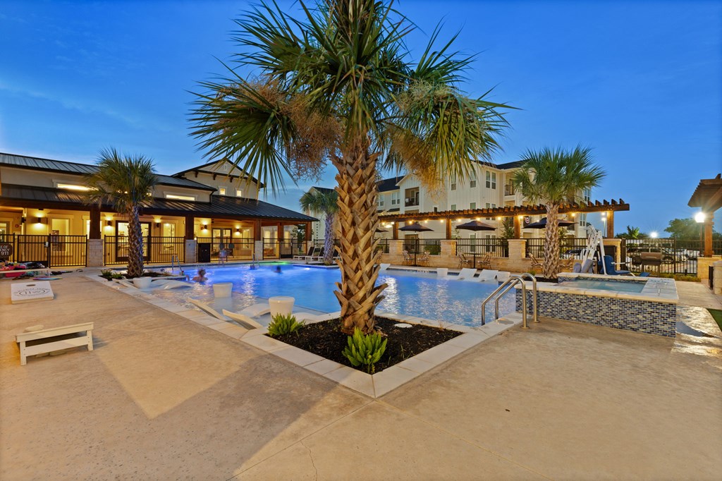 A palm tree stands in front of a pool at a resort.
