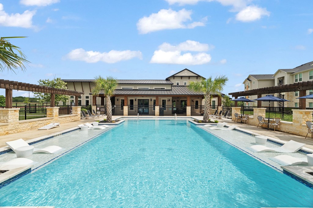 A large swimming pool in front of a building with a black fence around it.
