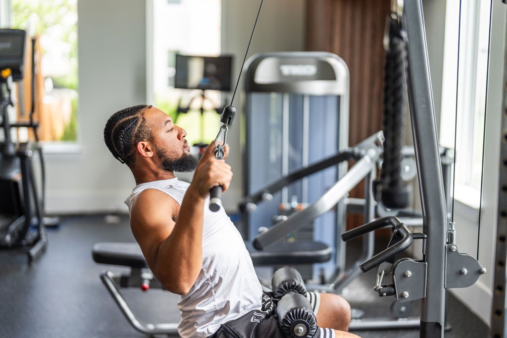 A man is working out in a gym using a cable machine.