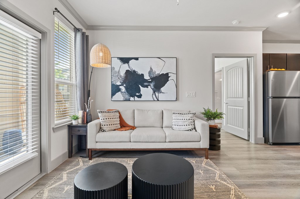 A modern living room with a white sofa, a large abstract painting, and a black coffee table.