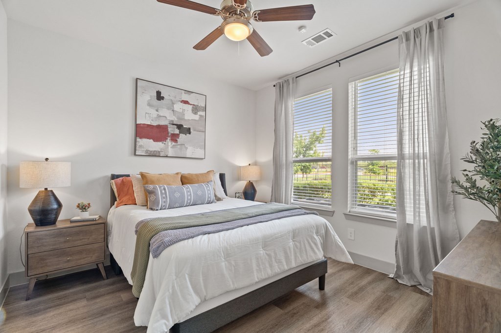 A bedroom with a bed, nightstand, and a ceiling fan.
