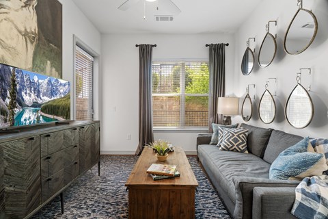 A living room with a grey couch, a wooden coffee table, and a large painting on the wall.