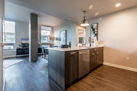A modern kitchen with stainless steel appliances and wooden flooring.