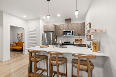 A kitchen with a white counter and wooden bar stools.