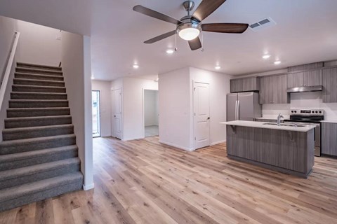A modern kitchen with a staircase on the left side.