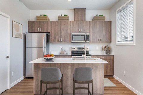 A kitchen with a white counter top and grey chairs.