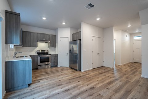 A modern kitchen with wooden floors and stainless steel appliances.
