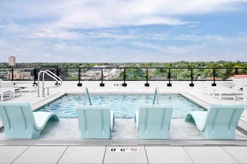A pool with four chairs and a white railing.