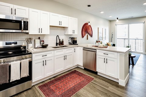 A kitchen with white cabinets and a red rug on the floor.