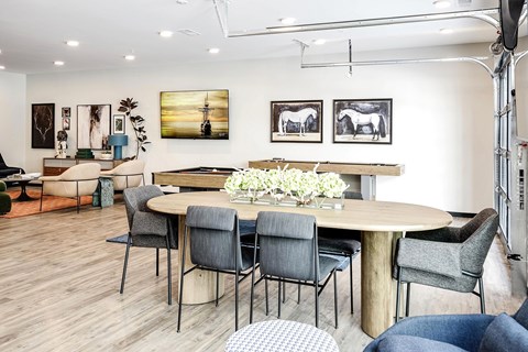 A modern dining room with a round table and grey chairs.