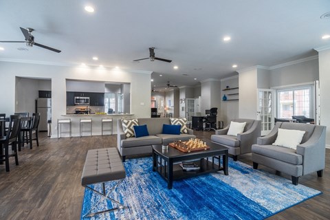 A modern living room with a blue rug and a chess board on the coffee table.