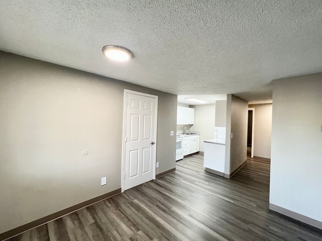 the spacious living room with white walls and wood flooring