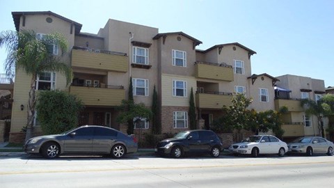 A row of houses with cars parked in front.