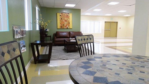 A living room with a brown leather couch, a checkered chair, and a round table with a mosaic design.