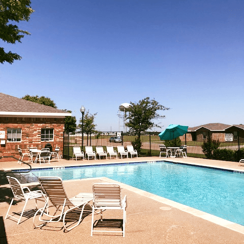 a swimming pool with white chairs and a umbrella