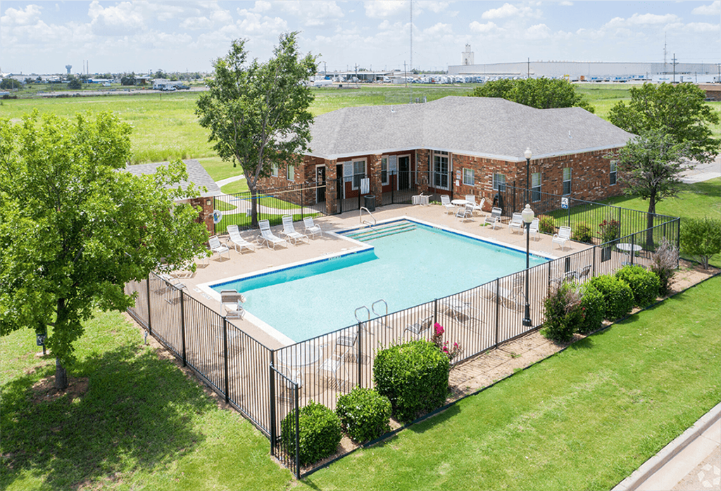 an aerial view of a swimming pool with a house behind a fence