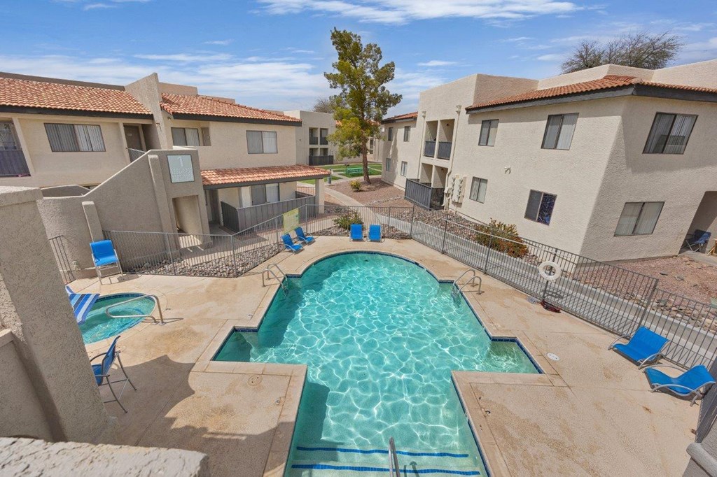 A swimming pool surrounded by chairs and buildings.