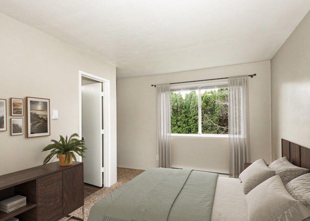 A bedroom with a bed, nightstand, and window with curtains.