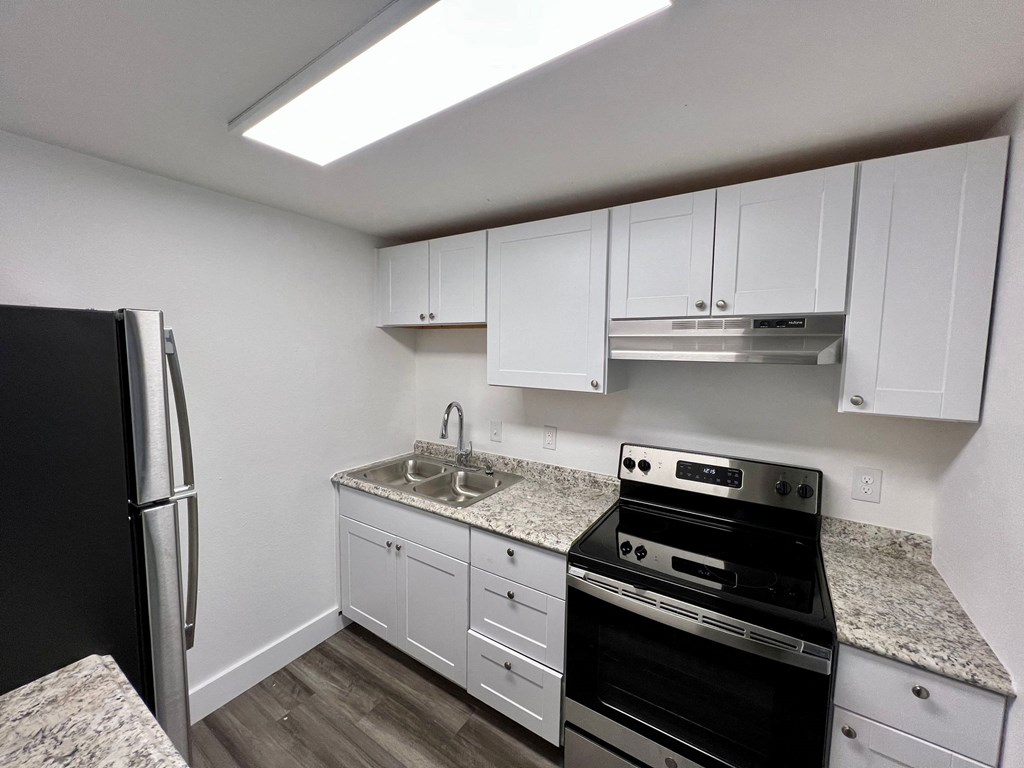 a kitchen with white cabinets and black appliances and granite counter tops