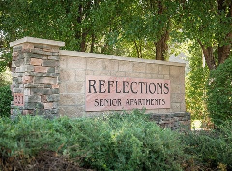 a sign for resettlement senior apartments in front of trees