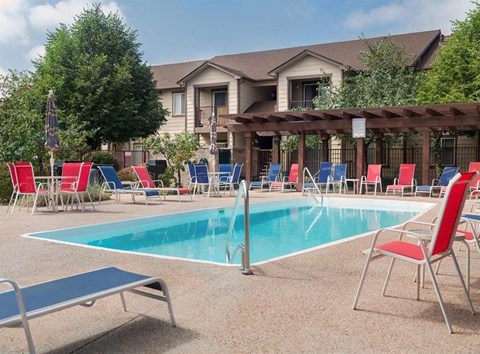 a swimming pool with red chairs and blue chairs around it
