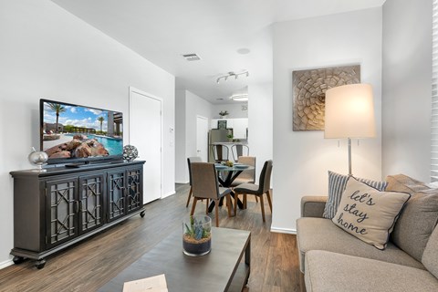 A living room with a grey couch, a wooden table, and a painting on the wall.