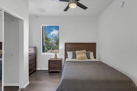 A bedroom with a bed, nightstand, and window.