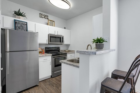 A kitchen with a refrigerator, stove, and microwave.