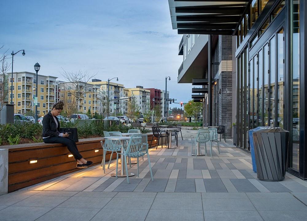 a woman sitting on a bench outside of a building using her laptop