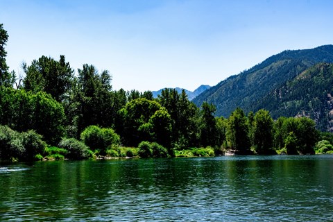 A serene lake surrounded by lush greenery and mountains.
