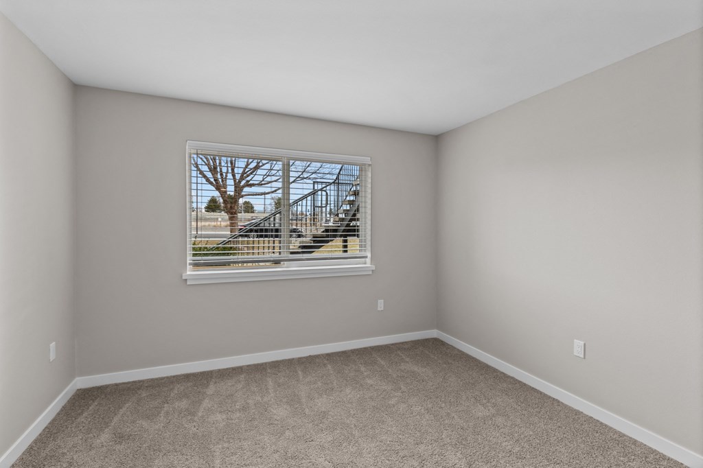 a bedroom with a large window and carpet