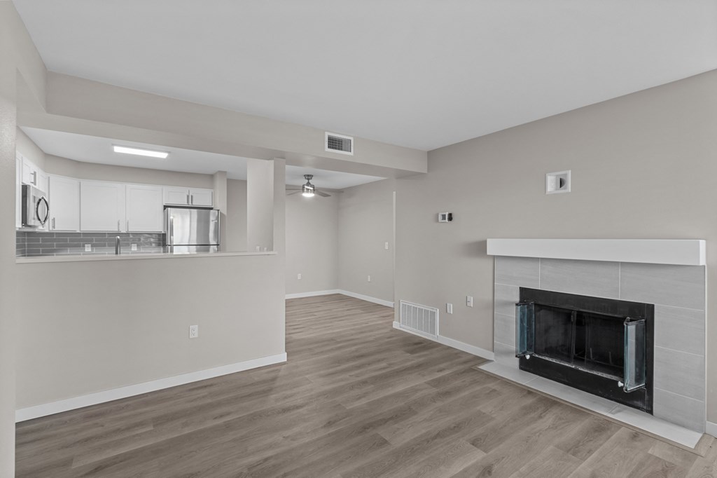 a living room with a fireplace and a kitchen in the background