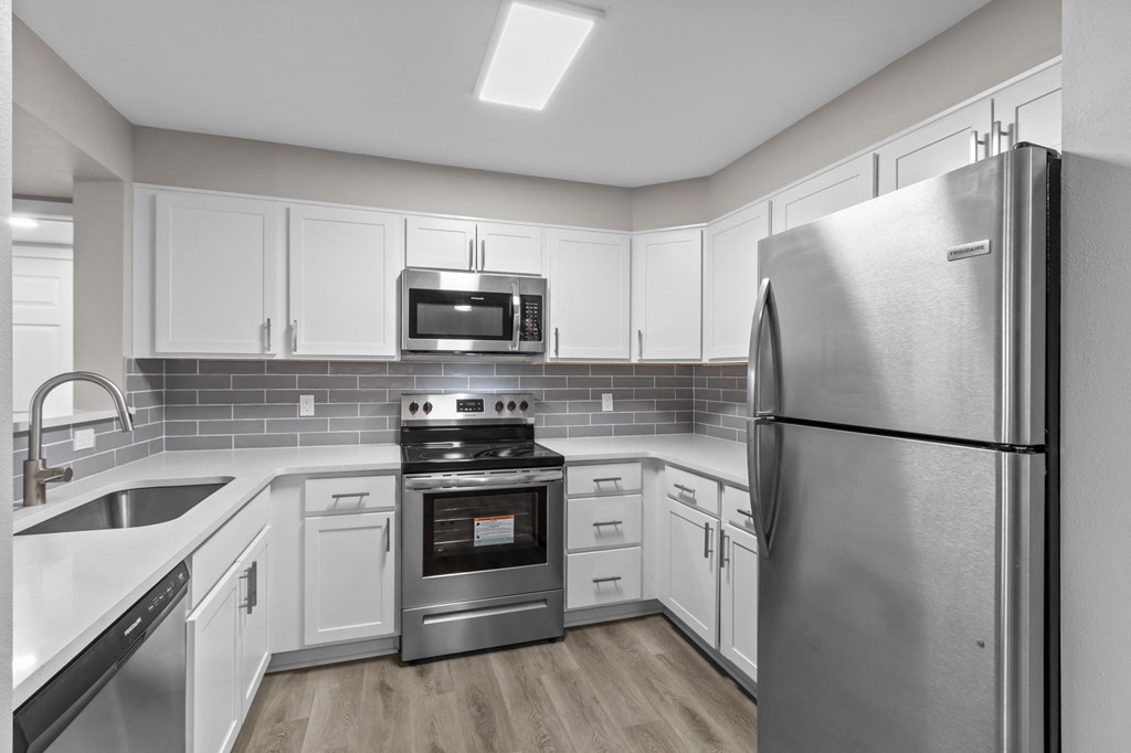 a kitchen with white cabinets and stainless steel appliances