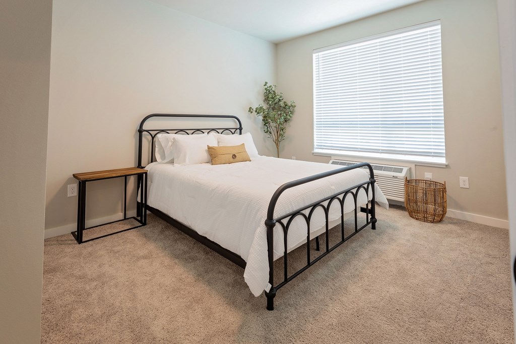 A bedroom with a bed, nightstand, and carpet.