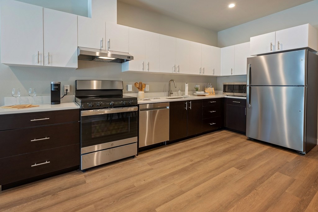 A modern kitchen with wooden floors and stainless steel appliances.