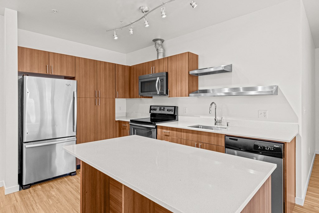 a kitchen with a white counter top and a stainless steel refrigerator