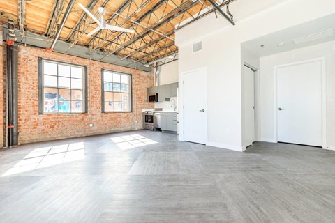 A large empty room with a brick wall and wooden ceiling.