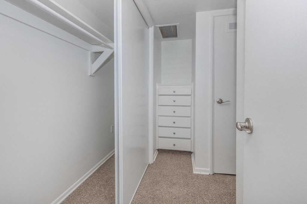 A white door is open to a hallway with a white dresser.