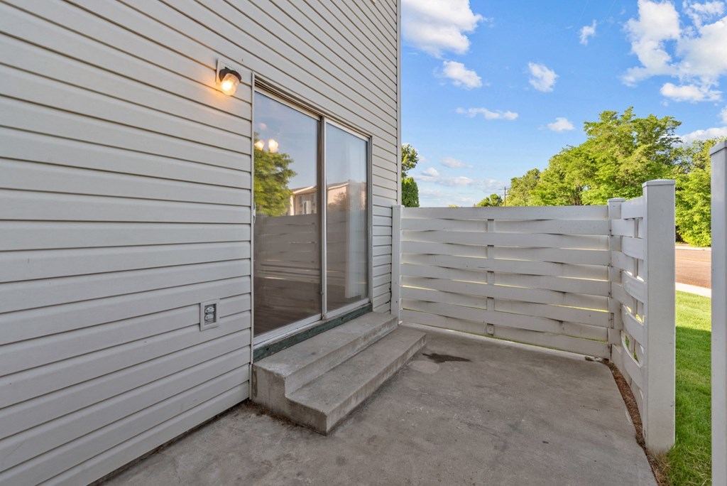 the backdoor of a house with a white fence and a glass door