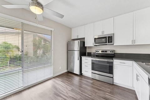 A kitchen with white cabinets and a stainless steel refrigerator.
